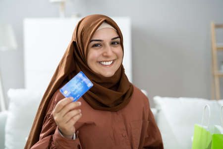Young Muslim Woman On Sofa Shopping Online With Credit Card