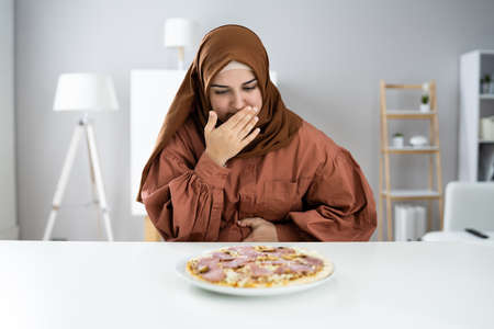 Woman Suffering From Stomach Pain While Having Pizzaの写真素材