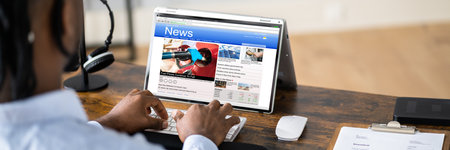 Businessperson Checking Online News On Laptop At Desk