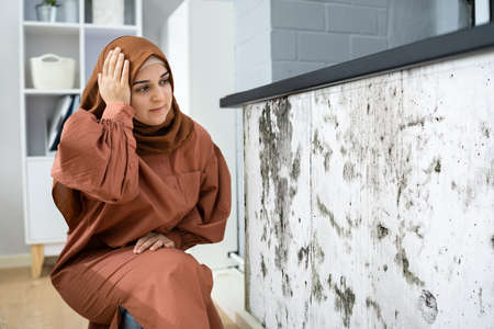 Close-up Of A Shocked Woman Looking At Mold On Wall