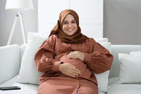 Pregnant Muslim Woman Waiting In Living Roomの写真素材