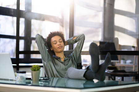 Businesswoman Sitting In Office Chair Relaxing Near Computerの写真素材