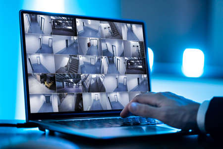 Security System Operator Looking At CCTV Footage At Desk In Officeの写真素材