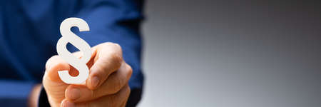 Close-up Of A Businessperson's Hand Holding Paragraph Symbol