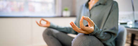 Young African Woman Sitting On Desk Meditating In Officeの写真素材