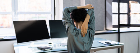 Stretching Arms In Office At Desk Rear View