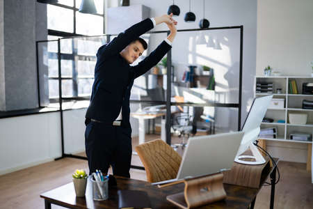 Arms Stretch Exercise Standing Near Desk In Officeの写真素材