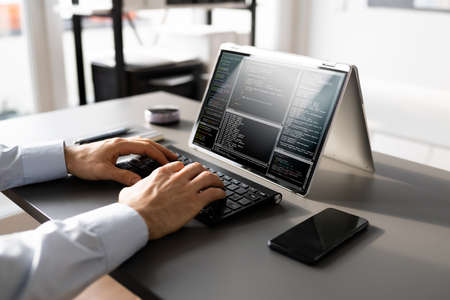 Computer Programmer Writing Program Code On Computer In Officeの写真素材