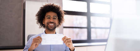 Holding Paycheck Or Payroll Check Or Insurance Cheque In Handの写真素材