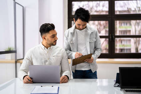 Two Happy Young Businesspeople Working On Computer In Officeの写真素材