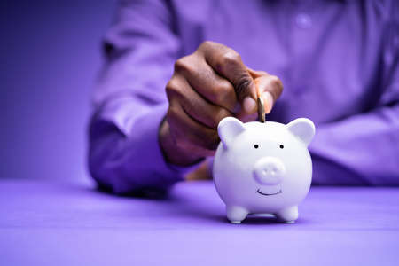 African Hand Putting Coin In Piggybank. Pension Money Fund