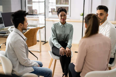 Young Multiracial Millennial Friends Sitting In Circle Having Group Discussion