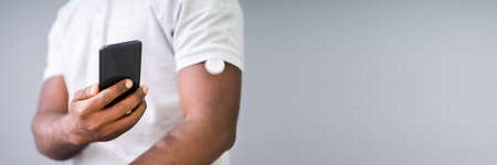 Man Testing Glucose Level With Continuous Glucose Monitor On Mobile Phoneの写真素材
