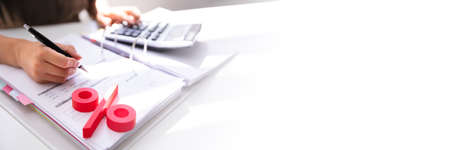 Close-up Of Red Percentage Symbol With Businessperson Calculating Billの写真素材