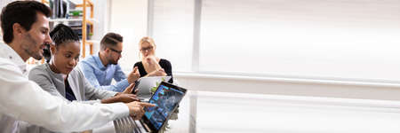 Side View Of Businesspeople Examining Graph On Computer At Workplace