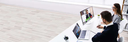 Two Young Businesspeople Video Conferencing On Computer At Officeの写真素材