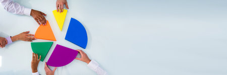 Businesspeople Hand Connecting Multi Colored Pieces Of Pie Chart On Deskの写真素材