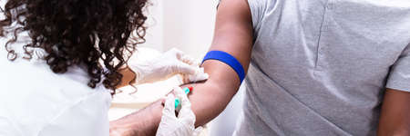 Close-up Of Doctor Taking Blood Sample From Patient's Armの写真素材