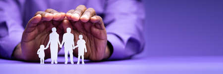 Businessperson's Hand Protecting Family Figure Cut Out