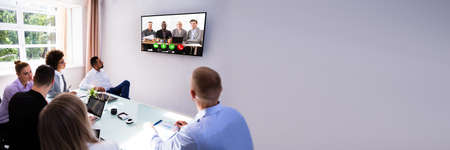 Group Of Skillful Businesspeople Video Conferencing In Boardroom