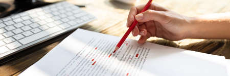 Close-up Of A Person's Hand Marking Error With Red Marker On Document