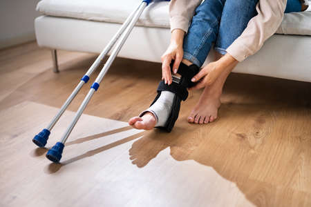 Woman With Leg Injury Using Crutches At Homeの写真素材