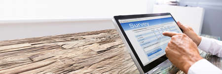 Close-up Of Businessman Looking At Online Survey Form On Digital Tablet