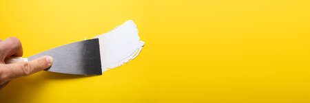 Close-up Of Painter's Hand Puttied Wall Using A Paint Trowel