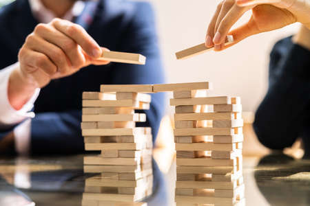 Close-up Of Human's Hand Placing Wooden Block Over Desk