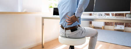 Young Businessman Having Back Pain While Sitting At Office Desk