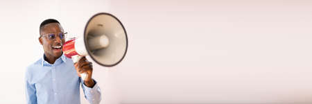 Close-up Of A Beard Man Shouting Through A Megaphone Against Gray Background