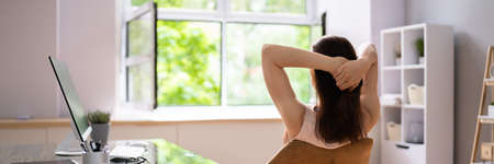 Relaxed Businesswoman With Hands Behind Head Sitting In Officeの写真素材