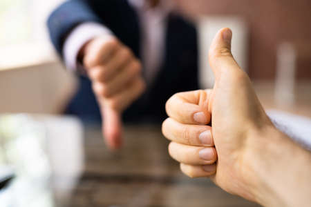Two Business People Showing Thumbs Up And Thumbs Down Sign In Office