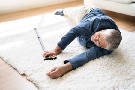 Senior Man Fallen On Carpet With Walking Stickの写真素材