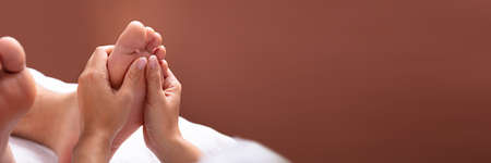 Close-up Of Therapist Hand Giving Foot Massage To Manの写真素材