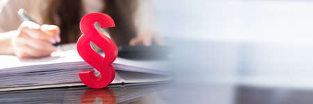 Close-up Of A Red Paragraph Symbol In Front Of Person Working At Workplace