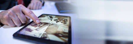 Close-up Of A Businessman Looking At CCTV Camera Footage On Digital Tablet