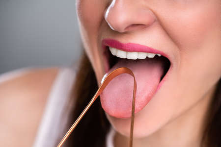 Close-up Of A Woman Cleaning Her Tongue With Cleanerの写真素材