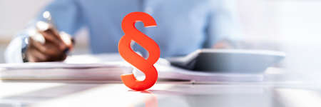 Close-up Of A Red Paragraph Symbol In Front Of Person Working At Workplace