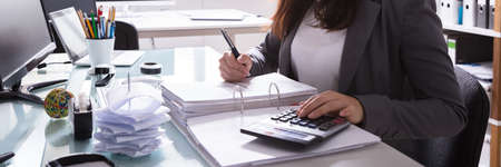 Happy Young Businesswoman Calculating Bill With Calculator