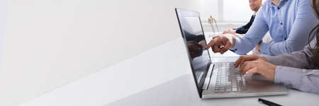 Close-up Of Business People Working On Laptop At Desk In Officeの写真素材