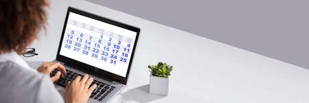 Close-up Of A Businesswoman Looking At Calendar With Daily Agenda On Laptop Computerの写真素材