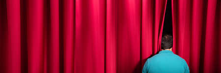 Rear View Of A Man Peeking Through A Red Stage Curtainの写真素材