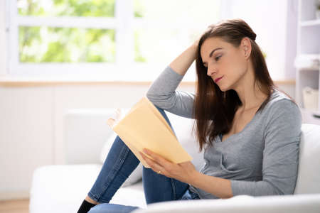 Adult Person Sitting On Sofa Reading Book. Relaxation Lifestyleの写真素材