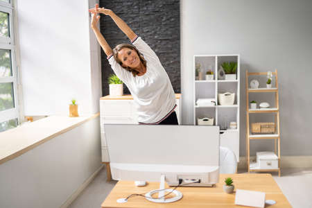 Young Businesswoman Stretching Her Arms At Desk