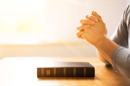 Sunlight Falling On Woman's Hand Over Holy Bible Bookの写真素材
