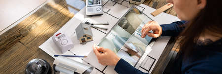 Person Watching Footage On Digital Tablet With Security Equipment On Blueprint