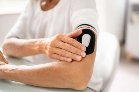 Close-up Of A Woman Testing Glucose Level With A Continuous Glucose Monitor On Her Arm