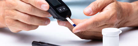 Close-up Of A Man's Hand Checking Blood Sugar Level With Glucometer