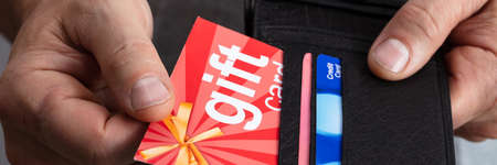 Close-up Of A Human Hand Removing Red Gift Card From Wallet